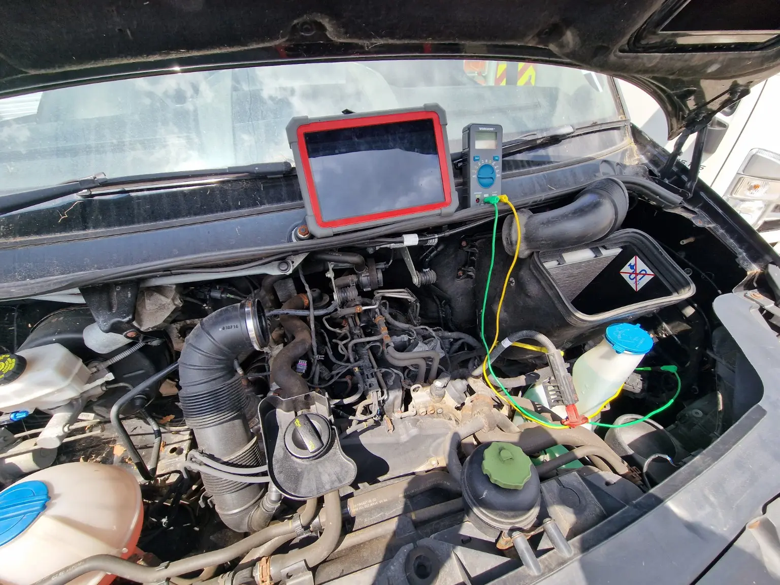Diagnostic tablet and multimeter connected to a vehicle